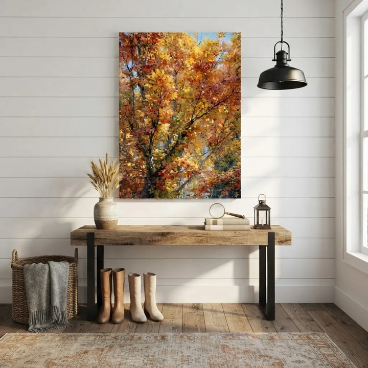 A vertical canvas wall art print depicting vibrant autumn trees with orange, yellow, and red leaves, styled in a rustic home entryway above a wooden console table.