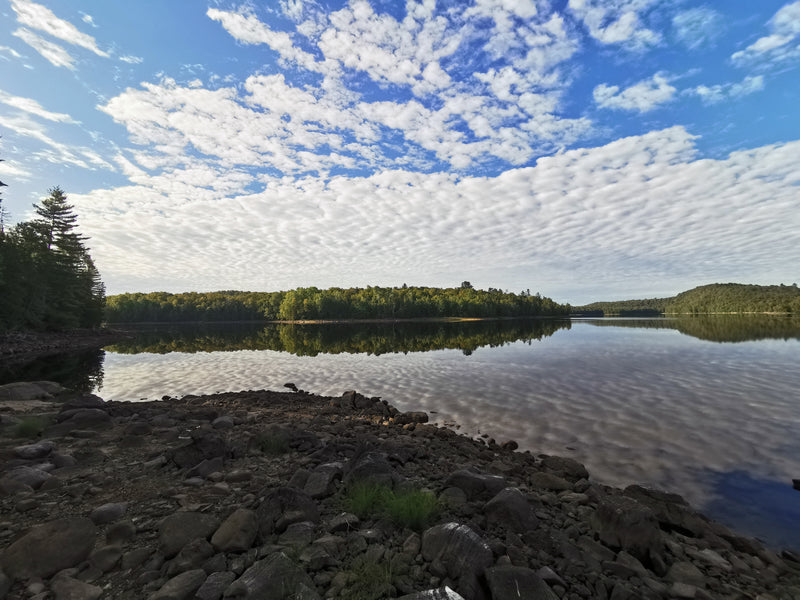 A still and tranquil mirror-like lake reflecting clouds and trees beautiful landscape - Bromont Media