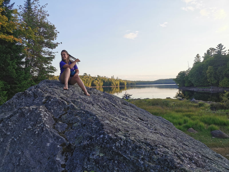 A woman on a large rock near a lake