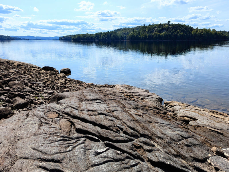 An ancient rocky shore eroded by the water on a beautiful lake - Bromont Media