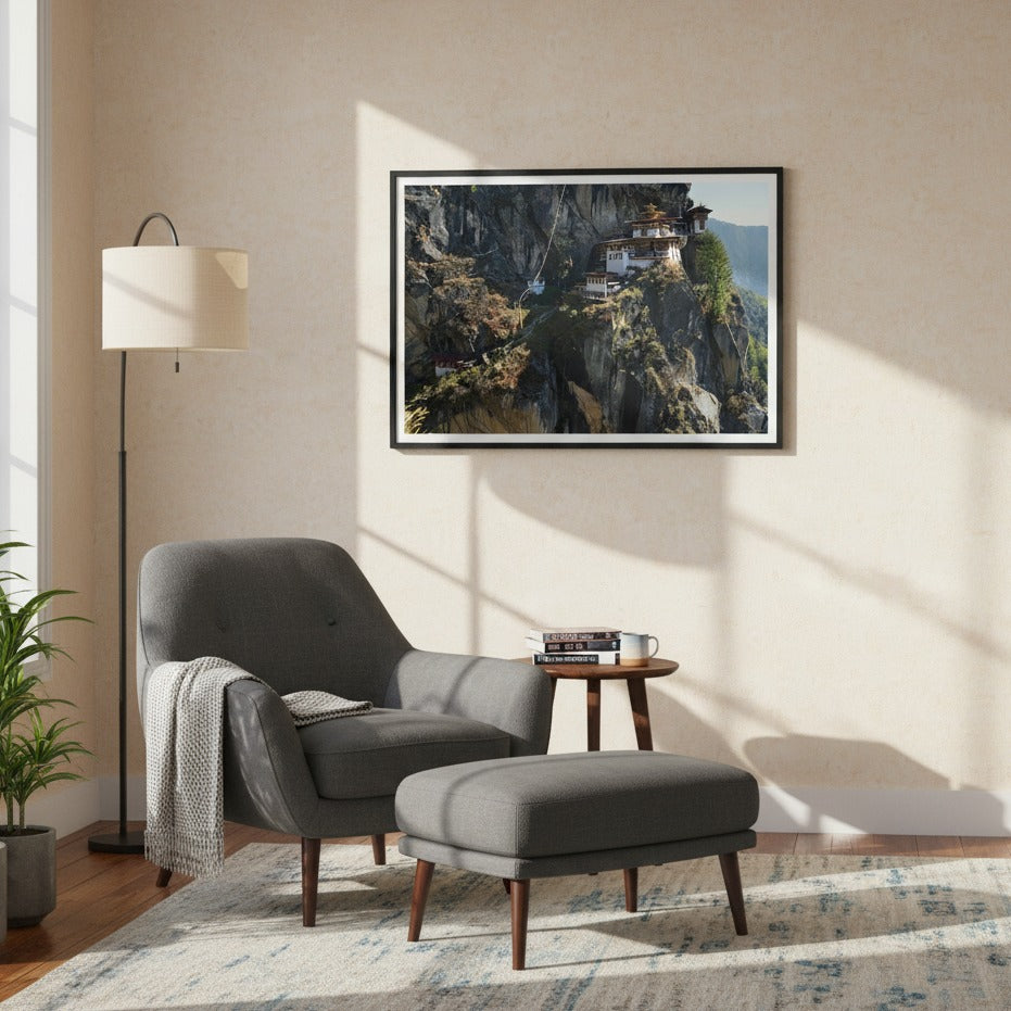 Modern living room with gray armchair, ottoman, and framed print of the Taktsang Monastery on the wall. - Bromont Media
