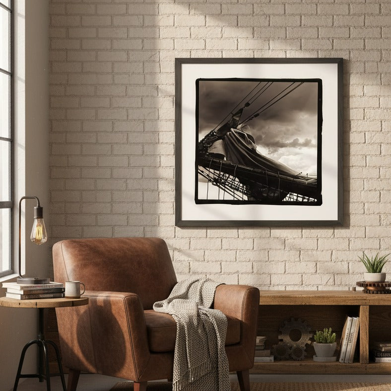 Cozy living room with a brown armchair, framed black and white artwork by Andrew Semple on a brick wall, and a wooden side table.