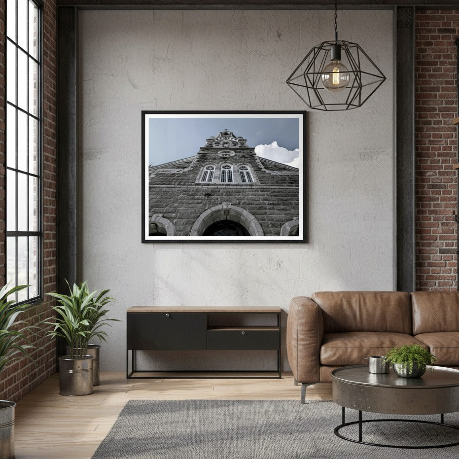 Living room with a framed picture of a church building on the wall, a brown sofa, and decorative plants - Studio Shefford