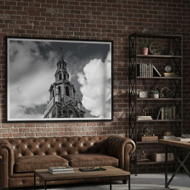 Living room with brown leather sofa, coffee table, and framed picture of a church steeple on brick wall - Studio Shefford