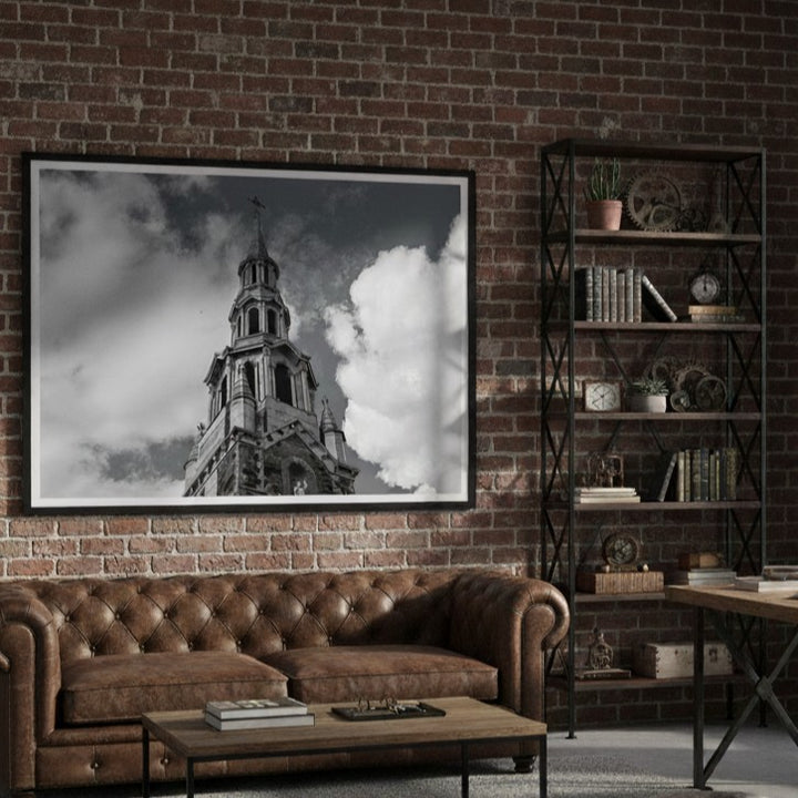Living room with brown leather sofa, coffee table, and framed picture of a church steeple on brick wall - Studio Shefford
