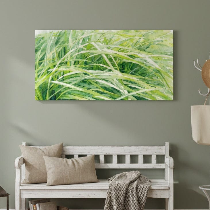 Green grass painting above a white bench with beige pillows and a blanket.