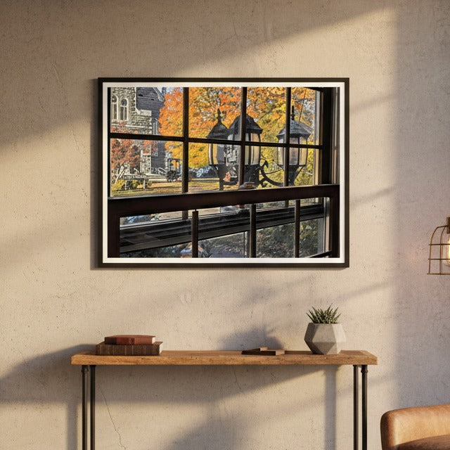 Framed artwork of a window view with autumn leaves by Studio Shefford on a wall above a console table.