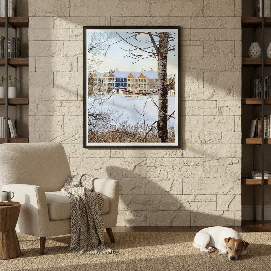 Framed artwork of a snowy landscape with houses by Studio Shefford on a stone wall in a living room.