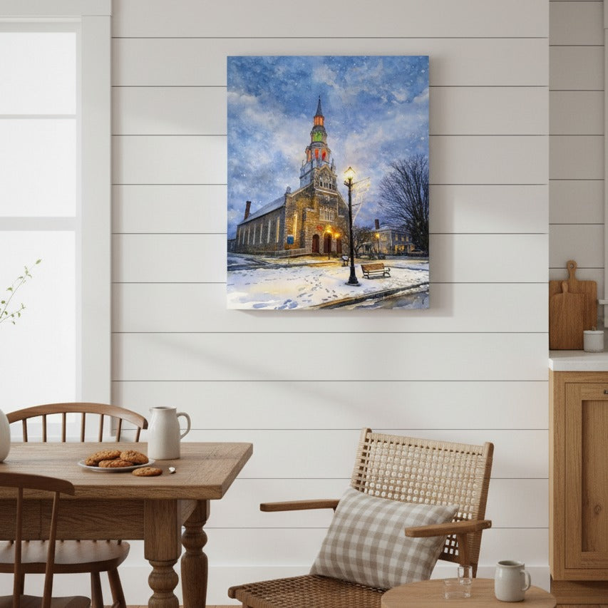Framed art of a snowy street scene with a church on a white wall above a wooden dining area.